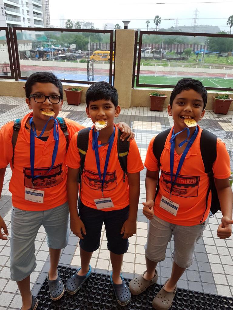 A picture of Ishaan Shah with his two team members, wearing the medals they won at the Regionals World Robotic Olympiad.